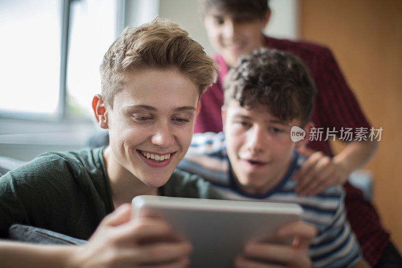 三个十几岁的男孩在家玩数字平板电脑游戏