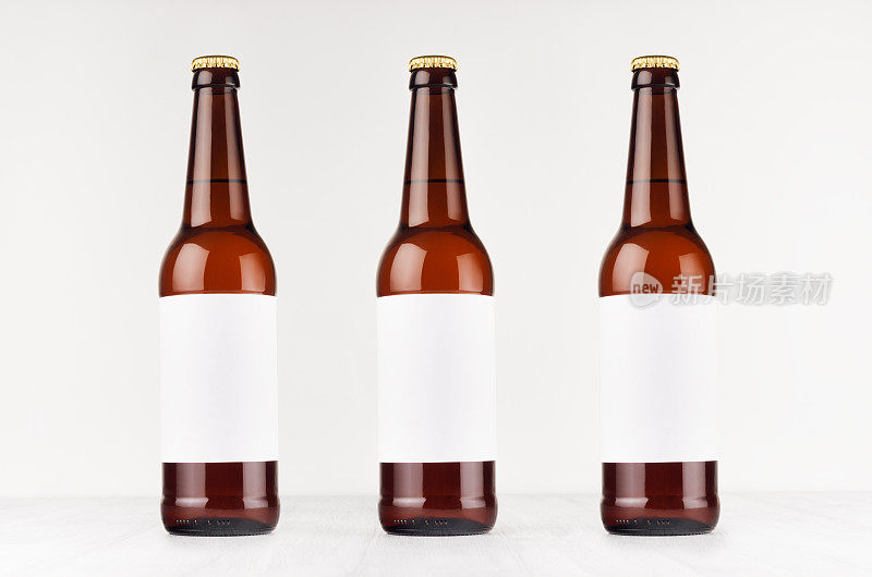 三个棕色长颈啤酒瓶500ml与空白白色标签在白色木板，模拟。