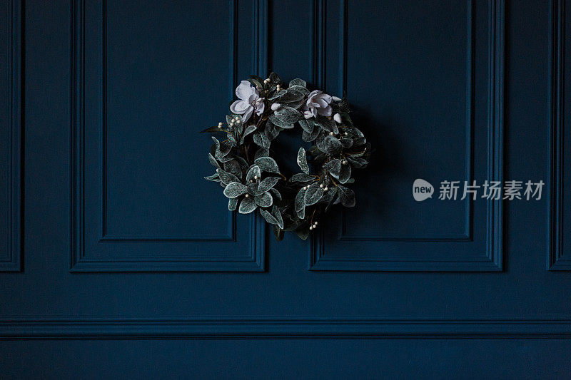 传统的圣诞装饰常青树花环与白色的花丝带在深蓝色的墙壁背景