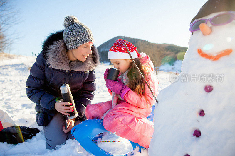 妈妈和女儿坐在雪撬上休息