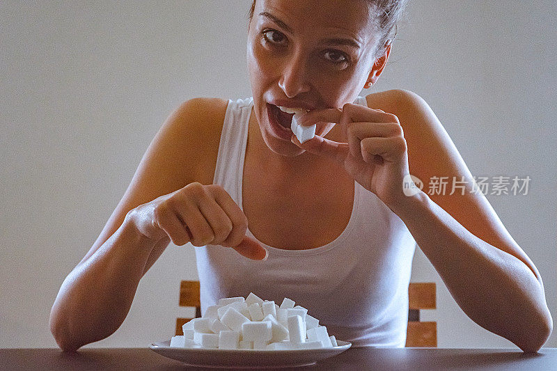 一个年轻女子在吃她面前盘子里的方糖的特写