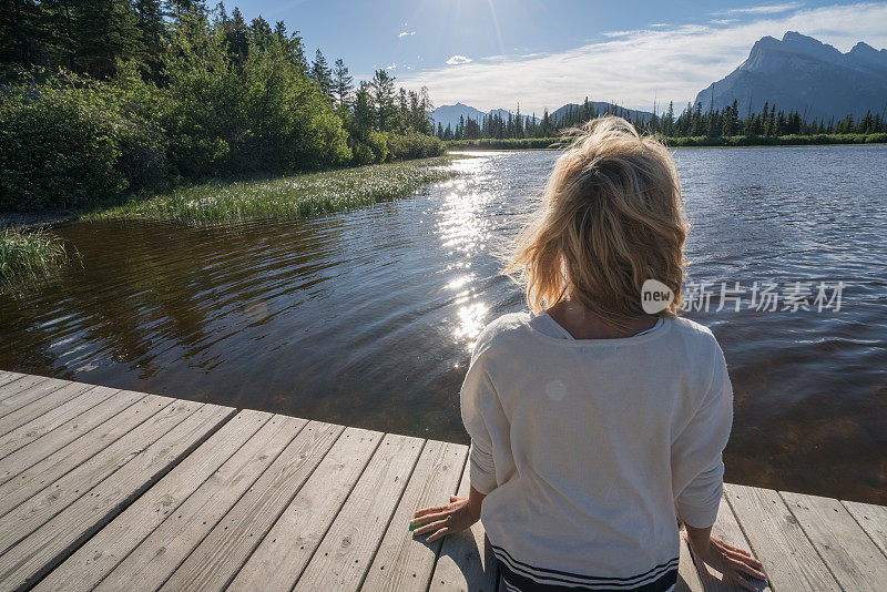年轻女子在湖边码头凝望大自然