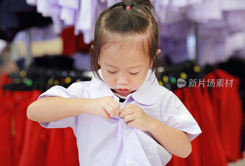 可爱的小女孩试着穿校服，幼儿园小朋友。