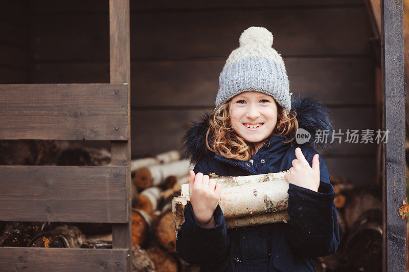 快乐的童女在冬天或秋天从棚子里捡柴火