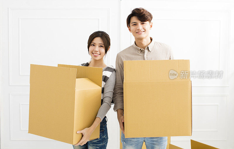 一对年轻夫妇正把箱子搬进新家