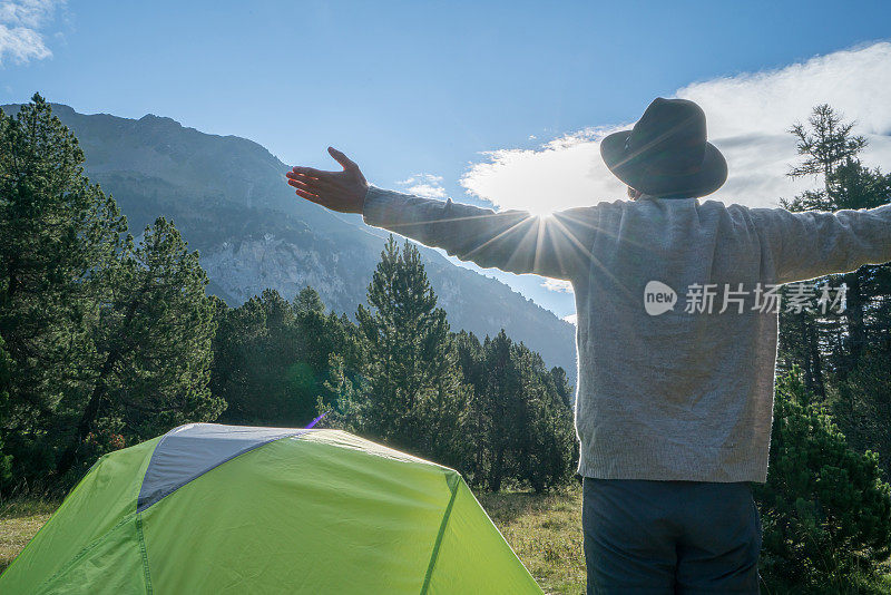 年轻人站在帐篷附近，伸开双臂，瑞士