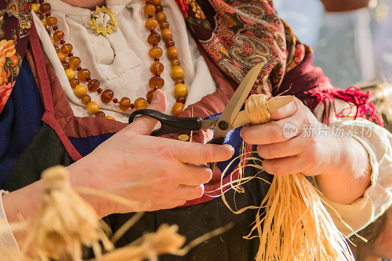 妇女在传统的俄罗斯衣服制作稻草娃娃