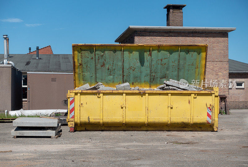 阳光明媚的日子里，巨大的黄色混凝土碎片集装箱