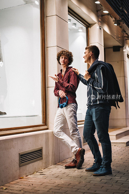 年轻的男性朋友在看商店橱窗里的衣服