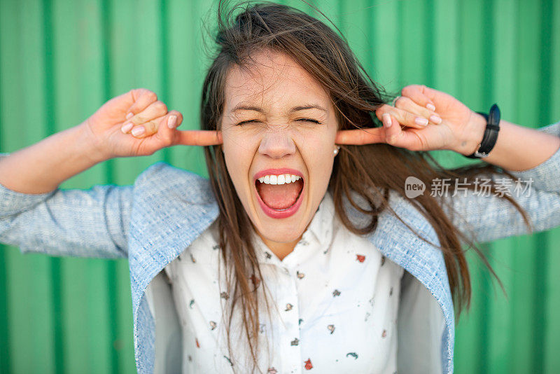 美丽的年轻的成年妇女在绿色的背景上做鬼脸