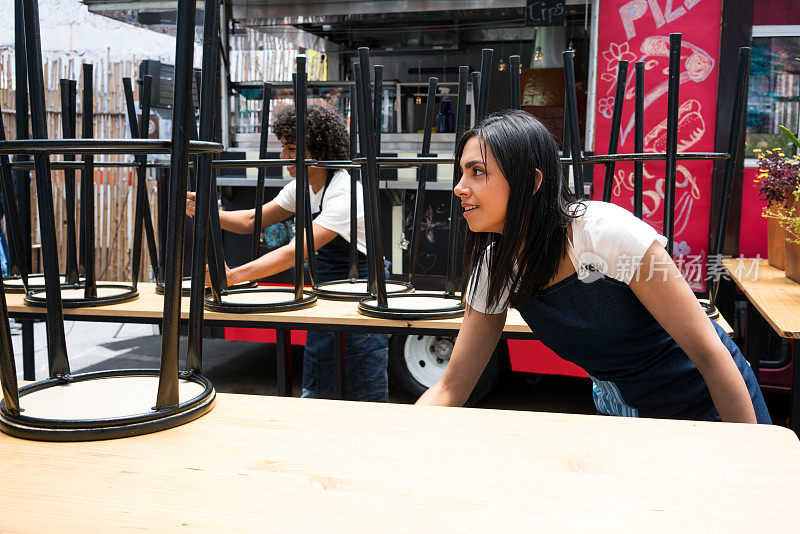 一家小型企业的拉丁工人在打开餐车前整理椅子