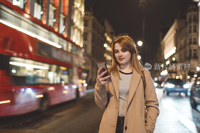 一个正在看手机的女人被伦敦的车流包围了