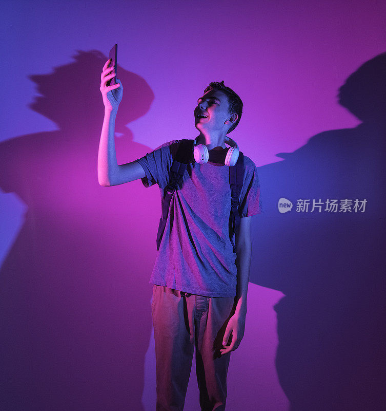 一个13岁的小男孩站在紫色和蓝色的灯下