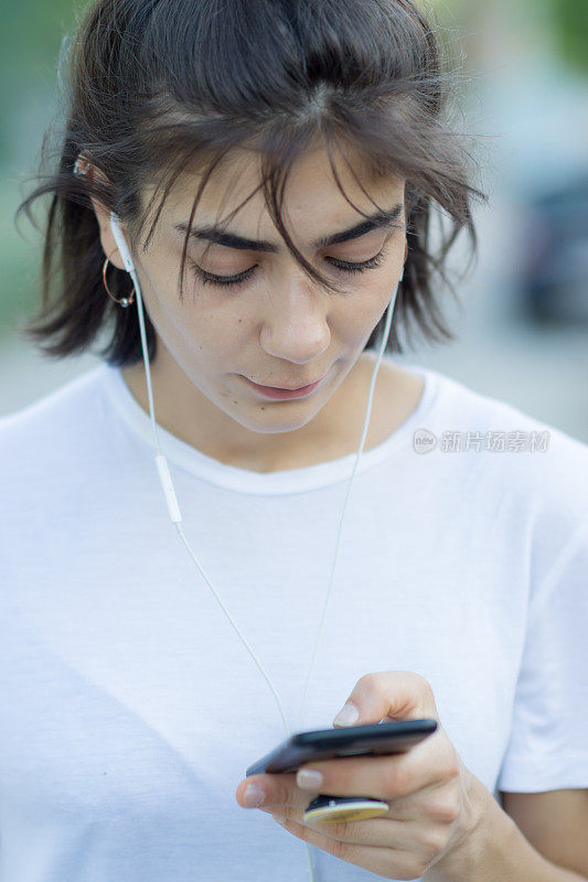 一个穿着运动服的年轻女子正在室外听手机里的音乐