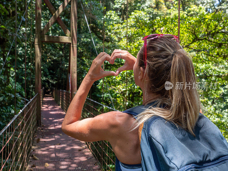 年轻女子在热带雨林制作心形手指架