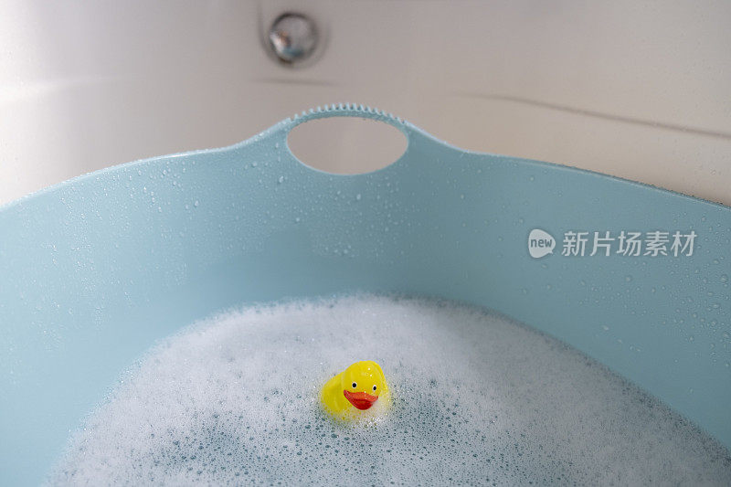 一只小黄鸭漂浮在泡沫的婴儿浴缸里