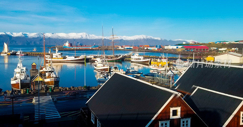 Húsavík，冰岛:清晨阳光明媚的海港，雪山