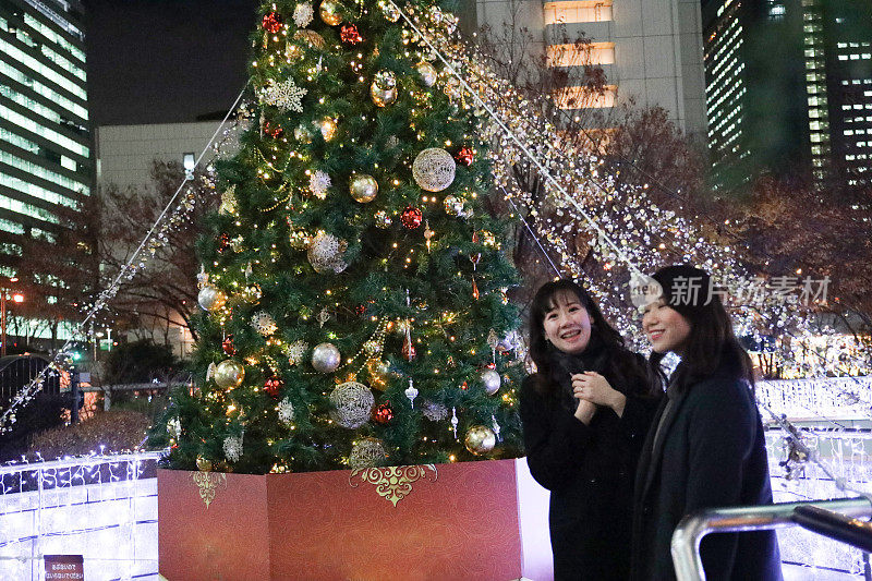 年轻漂亮的女人在圣诞彩灯里聊天