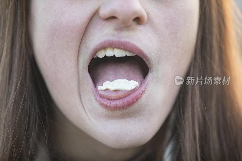 十几岁的女孩与口香糖在她的舌头上的特写