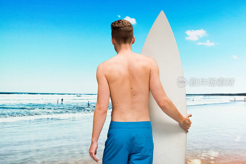 白人少年在自然面前谁在海边穿着短裤和使用冲浪板