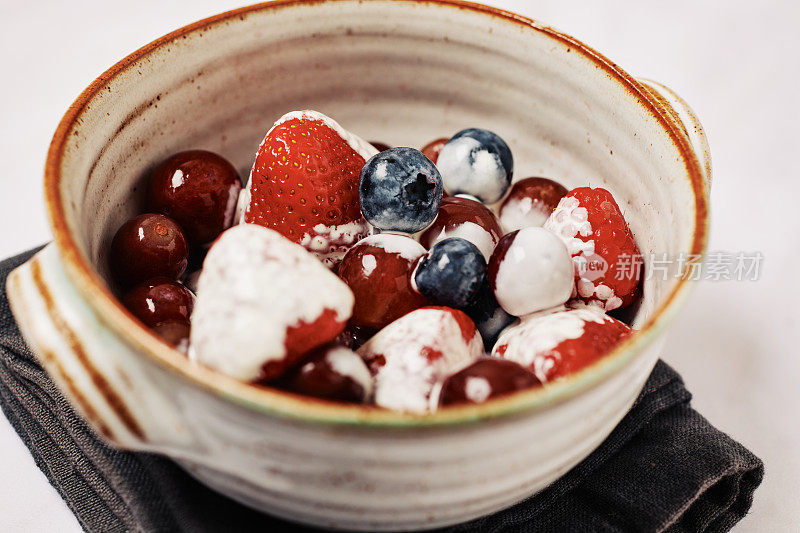 一碗水果、草莓、葡萄、蓝莓和覆盆子，淋上双层奶油。