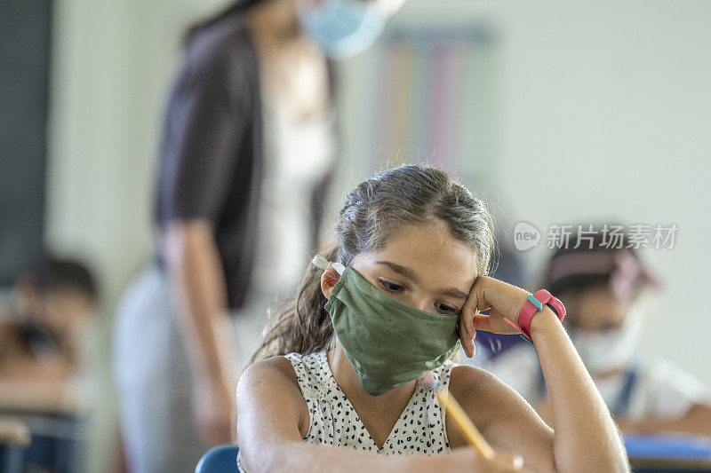 年轻的女学生在教室里戴着防护口罩