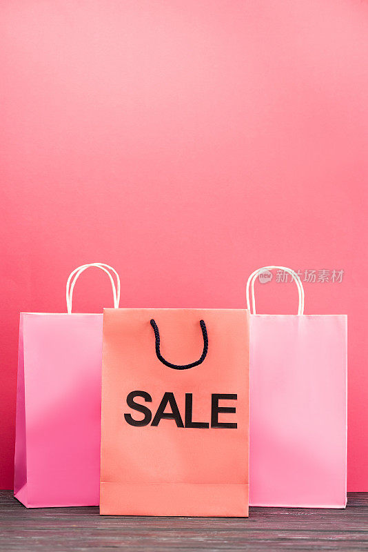 购物袋与销售字母附近的纸袋上的粉红色，黑色星期五的概念