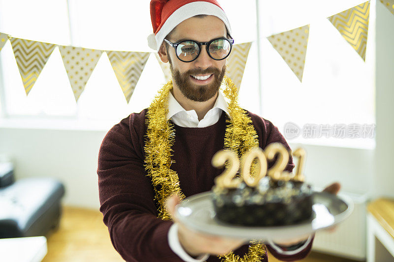 年轻女子在新年派对上玩得很开心，巧克力蛋糕上写着蜡烛数字2021，代表即将到来的新年