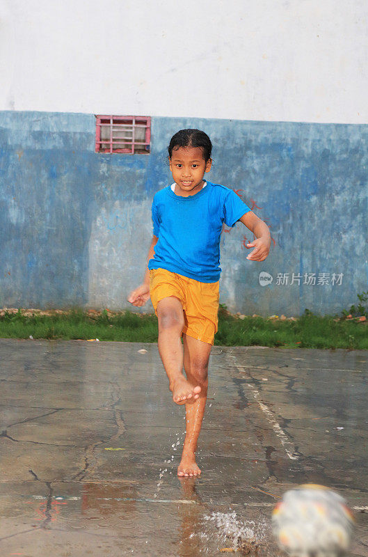 一个小女孩一边玩球一边打雨水