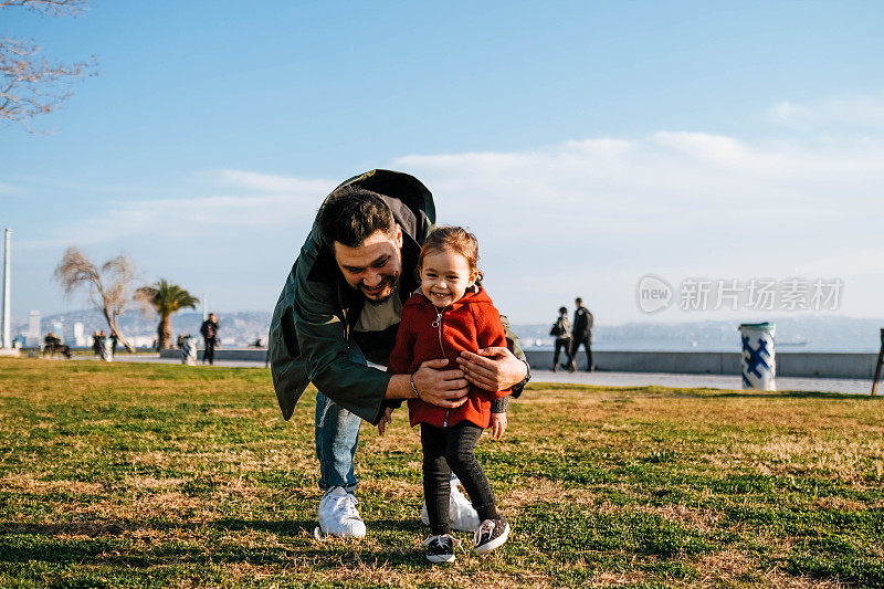 无忧无虑的年轻爸爸和女儿走在春天的日子。