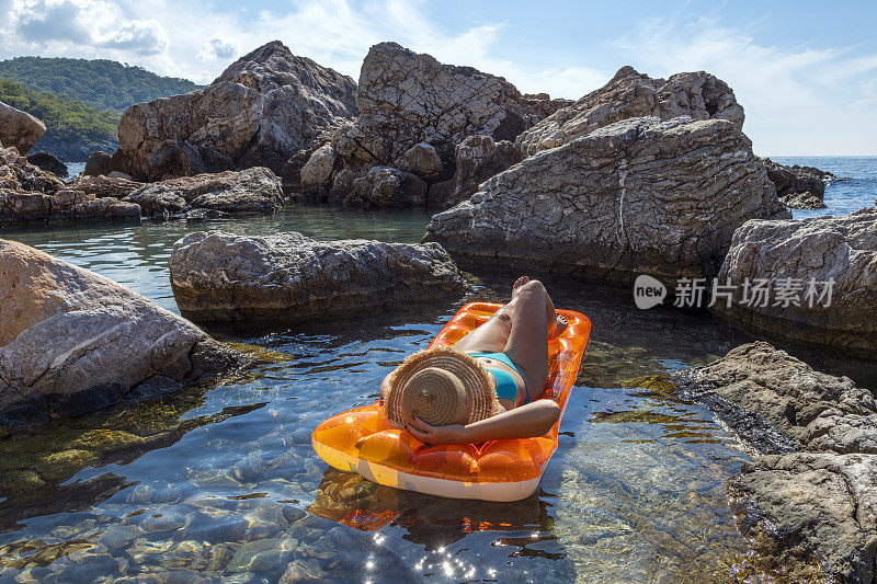 美丽的女人在海上的充气床垫上休息。