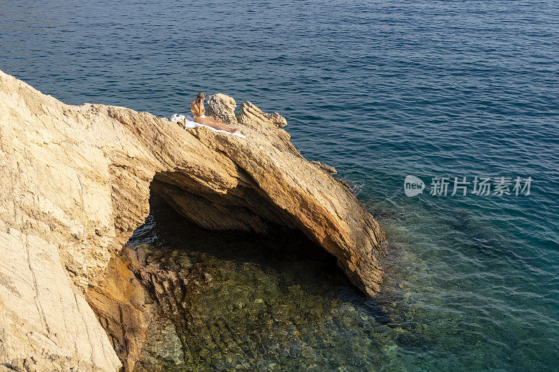 在海里的岩石上钻孔。女人在海里的洞里游泳。