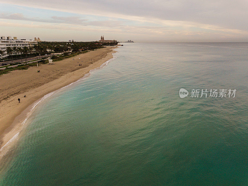 2021年1月18日，佛罗里达州棕榈滩海岸线上的蓝绿色海浪上的多云日出