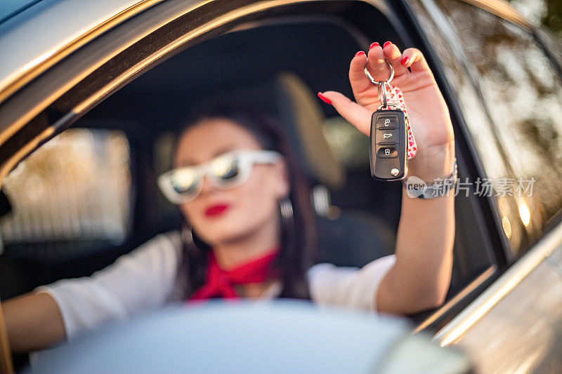 一个漂亮的女人坐在车里，手里拿着一把车钥匙。新司机。一个年轻的女人正在展示汽车钥匙。