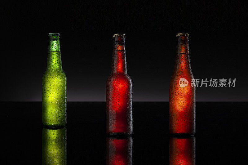 冰冷的棕色啤酒和绿色瓶子覆盖着冰和水滴-冷凝。空白饮料饮料产品设计模型。站在黑色的桌子上，黑色的背景。