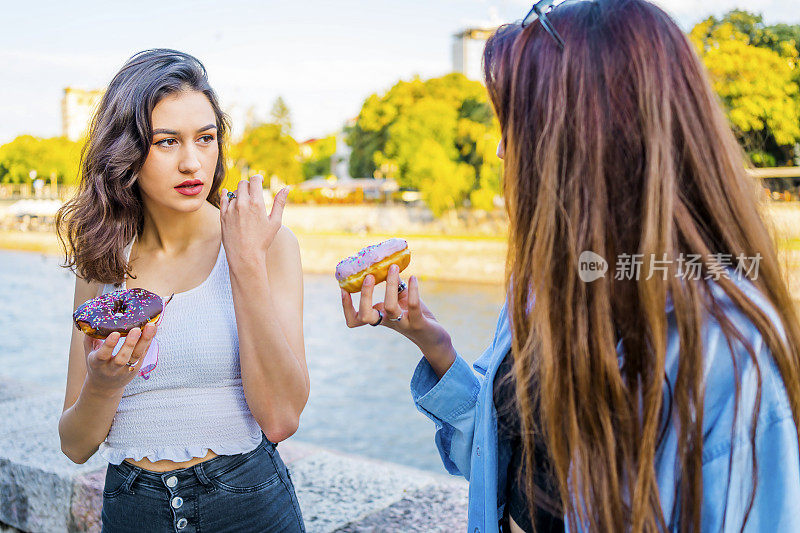 两个年轻女人在吃甜甜圈