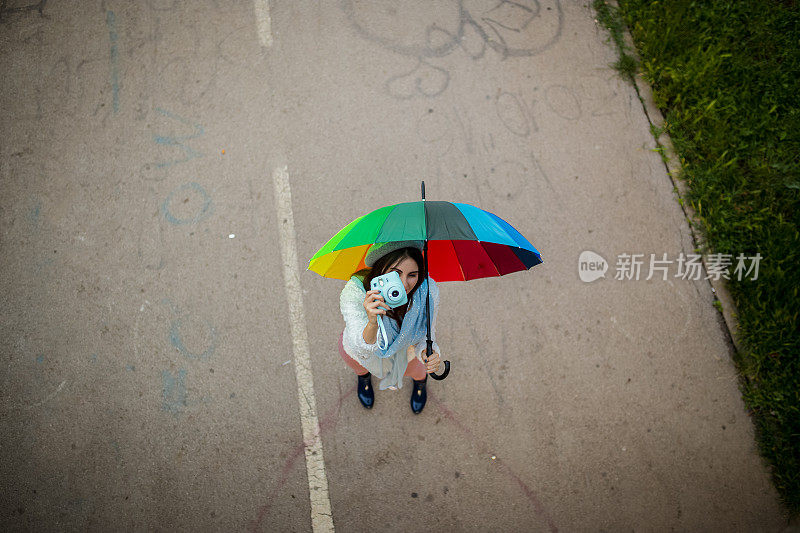 漂亮凉爽的女人带着五颜六色的雨伞在秋天的一天