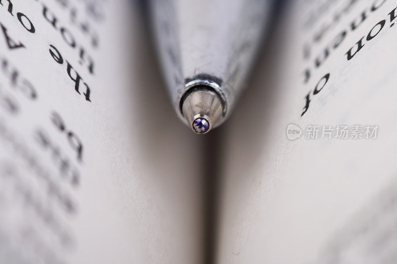 一支蓝色的圆珠笔夹在一本打开的书里