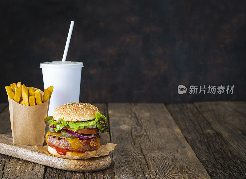 汉堡套餐，带走饮料吸管杯和一次性薯条在牛皮纸盒子在深色木桌上