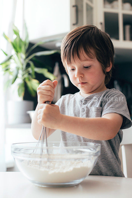 可爱活泼的小男孩，蹒跚学步的孩子在厨房揉面团。孩子们在家做猫面团。现实生活的时刻