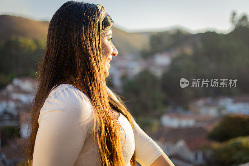 一位年轻的女旅行者在阳光明媚的日子里欣赏风景
