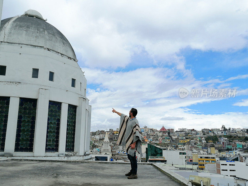 拉丁背包客在厄瓜多尔通古拉瓦的安巴托周围旅行时，指着大教堂的圆顶，放松和享受旅程;背面，城市景观在晴天多云的日子。