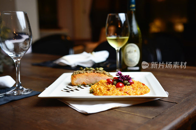 美味的烤三文鱼配根茎，白葡萄酒放在质朴的木桌上。