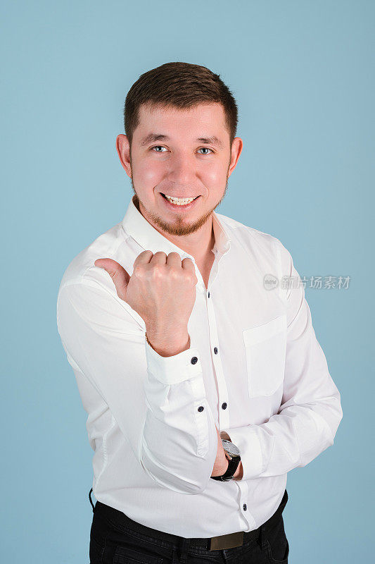 一名25岁至29岁、身穿白衬衫、留着胡须的男子用拇指指着竖着的照片