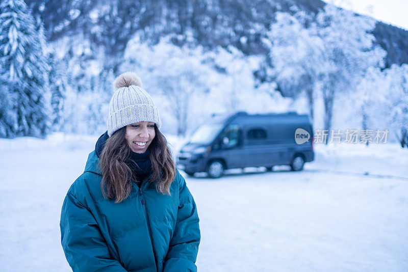 一名年轻女子将车停在雪山下的湖面上