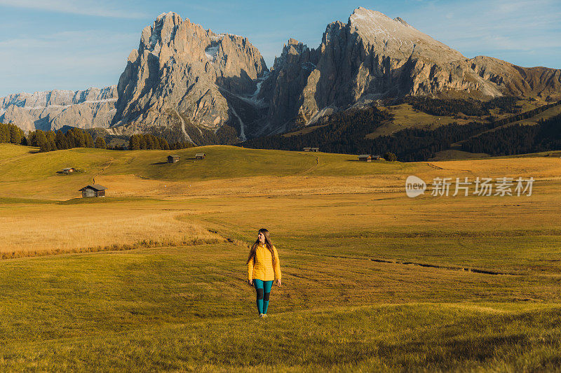 在白云石阿尔卑斯山脉的高山草地上散步，凝视夕阳美景的女游客