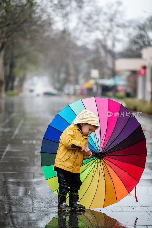 孩子们撑着五颜六色的伞，在水坑里跳跃，在雨中玩耍