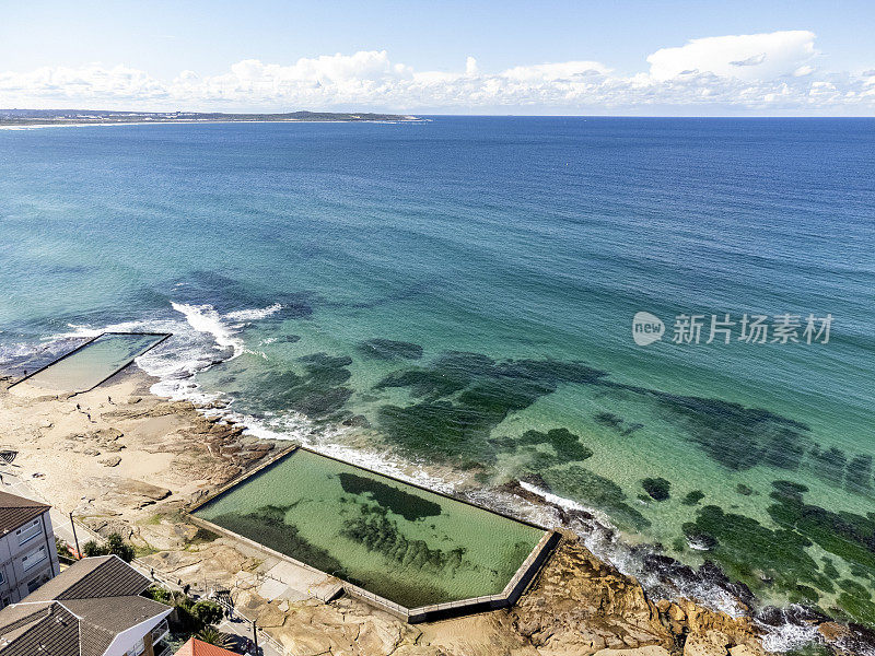 美丽的海滨小镇鸟瞰图，配有海洋游泳池，背景有复制空间