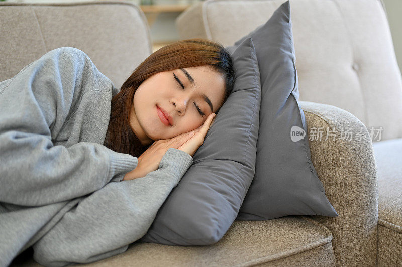 放松的年轻亚洲女性在沙发上午睡，在沙发上睡着了