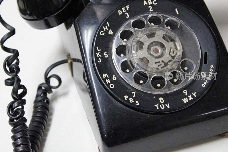 复古黑色旋转拨号电话与盘绕在古董店的线-白色背景